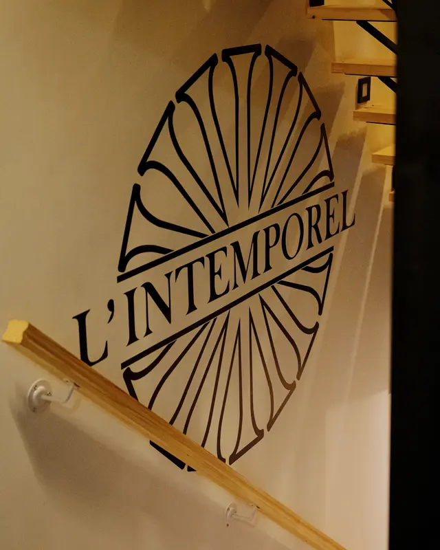 Le nom L’Intemporel peint sur le mur de l’escalier, dans la pénombre