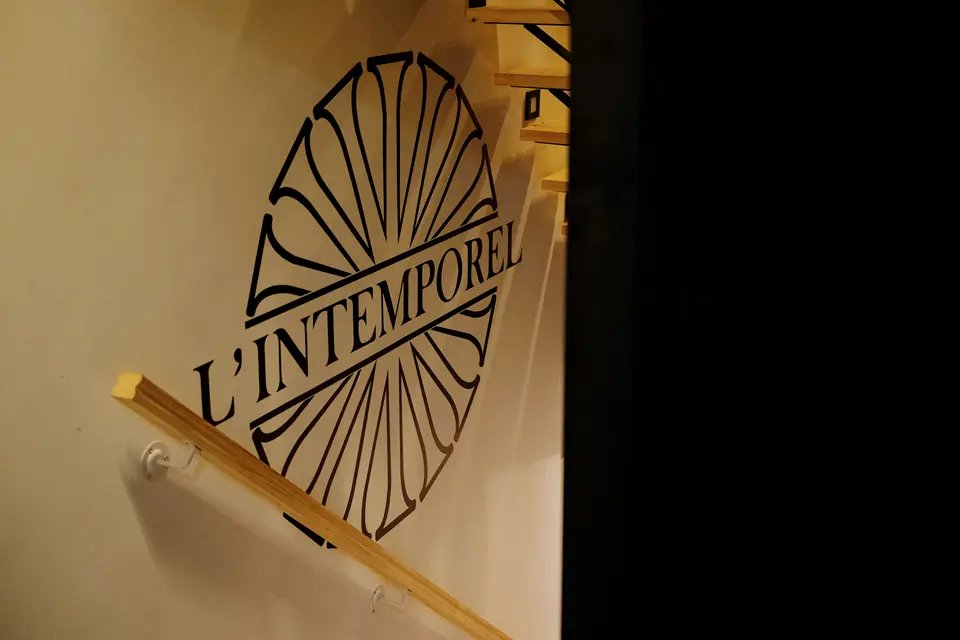 Le nom L’Intemporel peint sur le mur de l’escalier, dans la pénombre