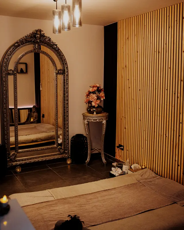Cabine aux murs en lattes de bois, grand miroir baroque argenté et futon au sol