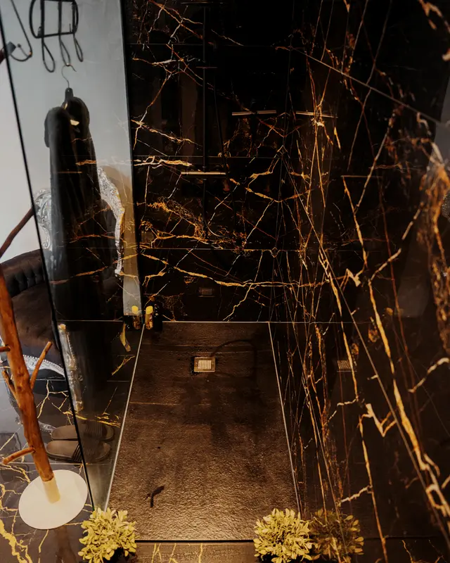 Douche à l’italienne en marbre noir veiné d’or, dans une cabine de L’Intemporel