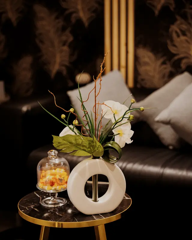 Le salon d’accueil de L’Intemporel : canapé de cuir noir et orchidée