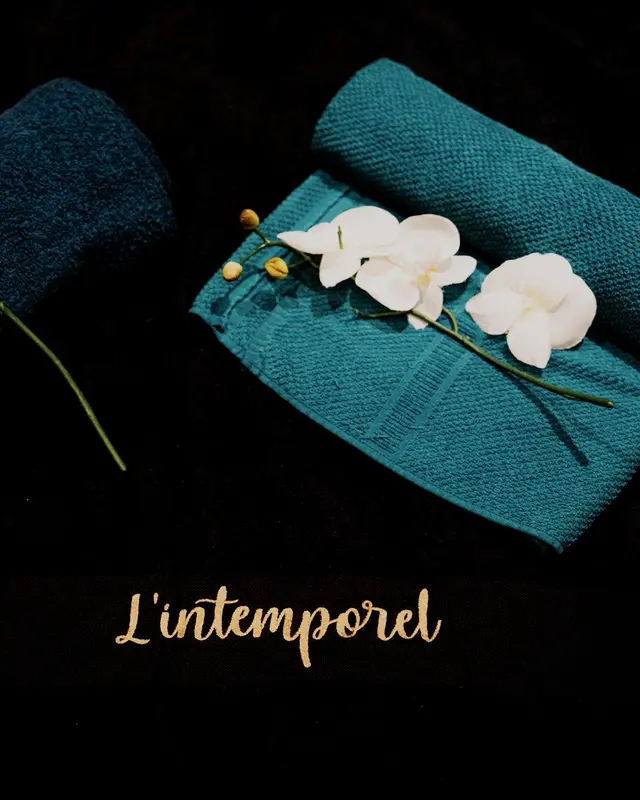 Linge noir brodé L’Intemporel, serviettes roulées et orchidées blanches