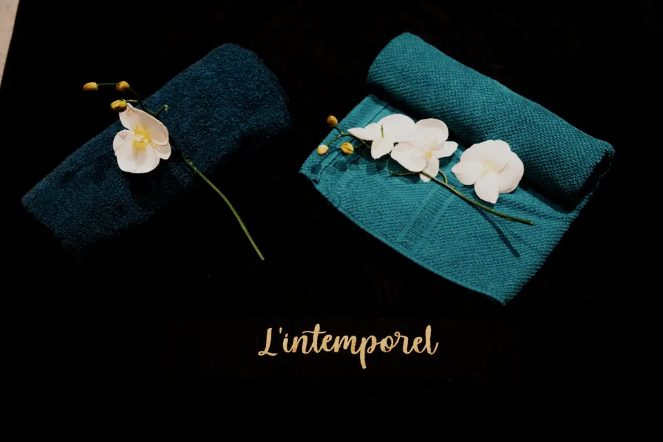 Linge noir brodé L’Intemporel, serviettes roulées et orchidées blanches